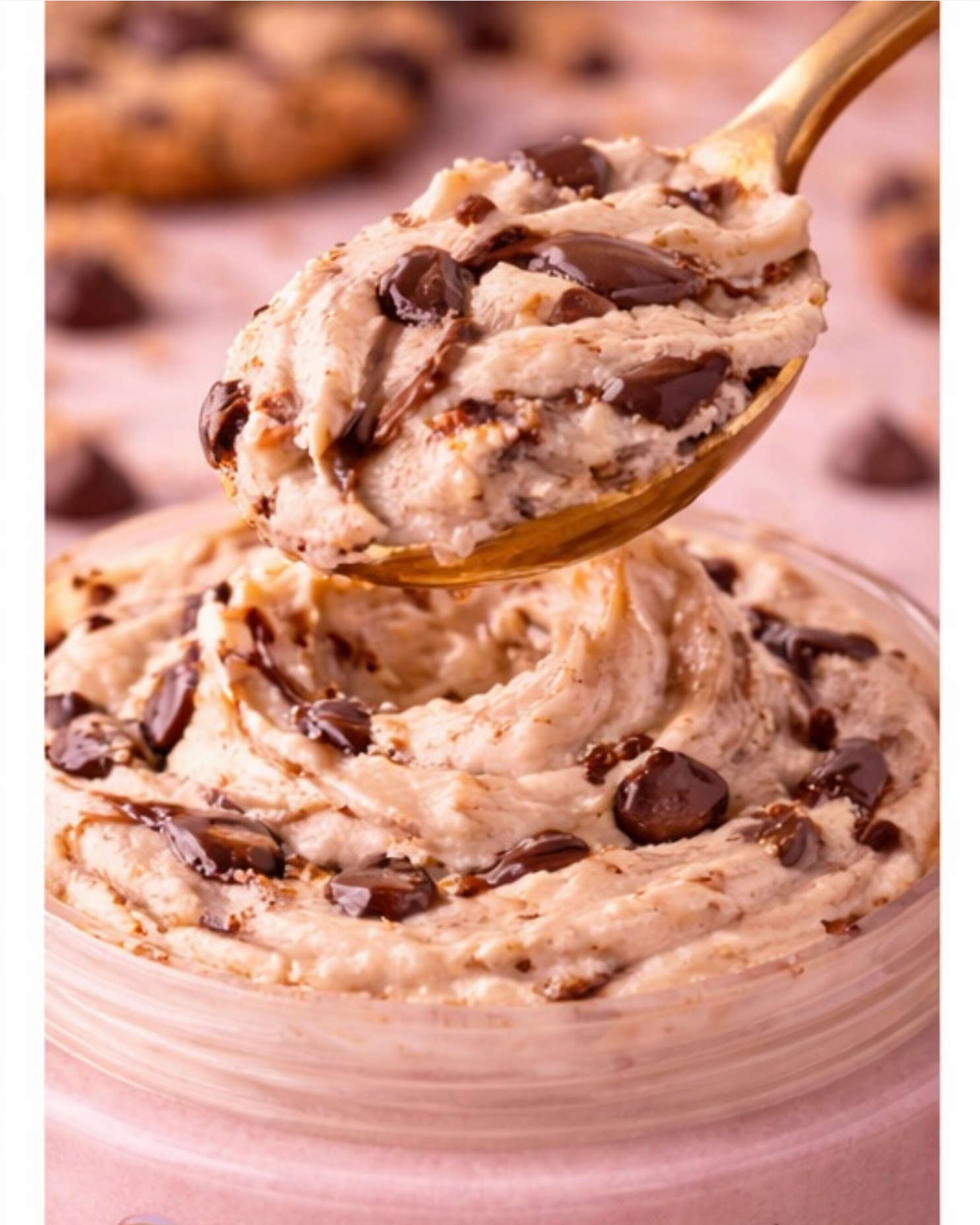 Spoonful of Cookie Monsta Body Butter with chocolate chips over a container of cookie dough.