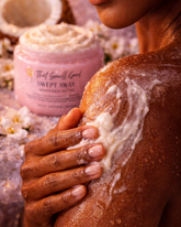 Person applying whipped body butter to their skin with a container of &